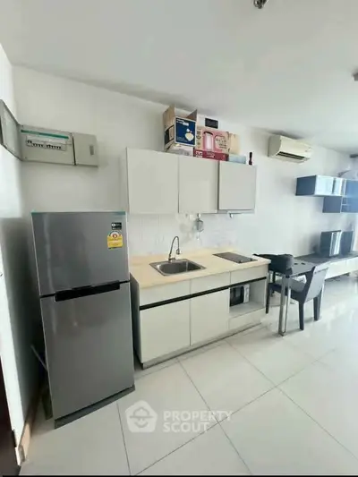 Modern kitchen with sleek cabinets, stainless steel fridge, and minimalist design in a bright apartment.