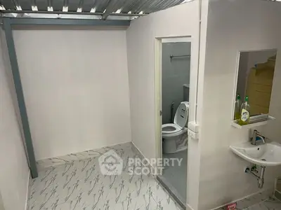 Modern bathroom with sleek design and white fixtures, featuring a toilet and sink in a compact space.