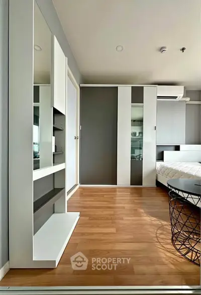 Modern bedroom with sleek design, featuring wooden flooring and built-in wardrobe for stylish living.