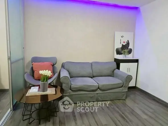 Modern living room with stylish gray sofa and accent chair, featuring elegant decor and ambient lighting.