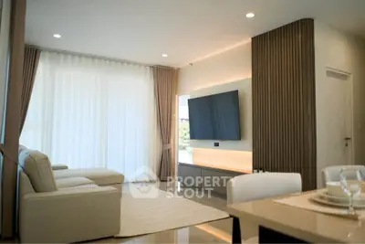 Modern living room with sleek design, featuring a wall-mounted TV and elegant furnishings.
