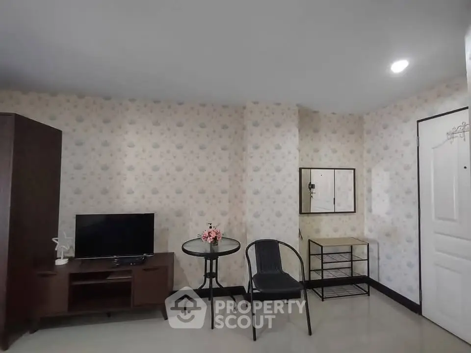 Cozy living room with TV, table, and chair in a stylish apartment.
