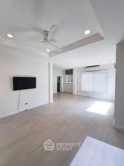 Spacious empty living room with modern ceiling fan and natural light