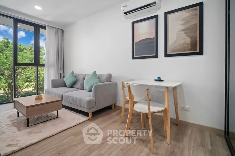 Modern living room with cozy sofa, stylish decor, and large window with lush green view.