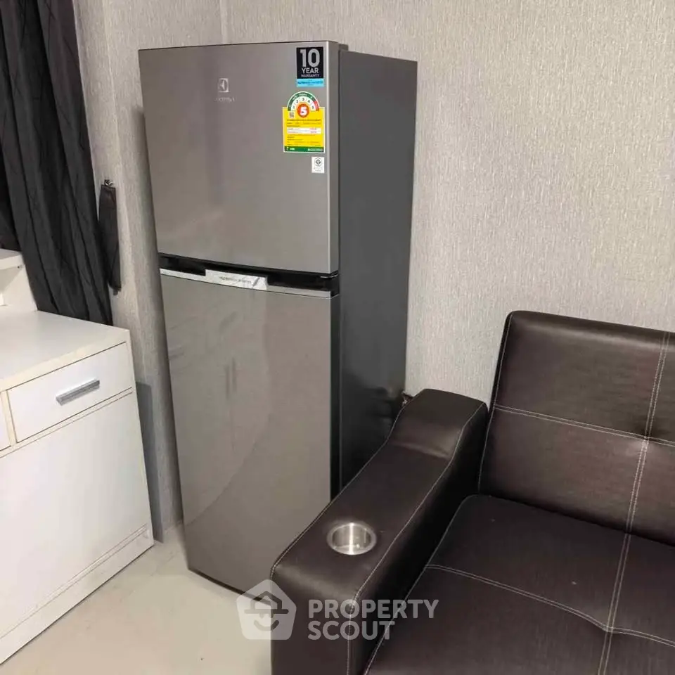 Modern apartment interior with sleek fridge and stylish leather sofa, perfect for urban living.