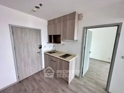 Modern compact kitchen with sleek cabinetry and electric stove in a minimalist apartment.