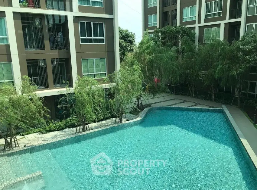 Modern apartment complex with a sparkling outdoor pool and lush greenery.