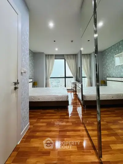 Spacious modern bedroom with wooden flooring and large window view