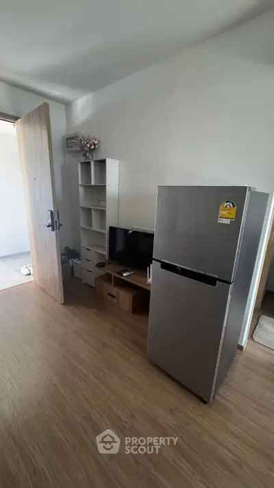 Modern interior with sleek fridge and minimalist shelving in a cozy living space.