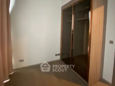 Spacious empty room with built-in wooden wardrobe and soft lighting.