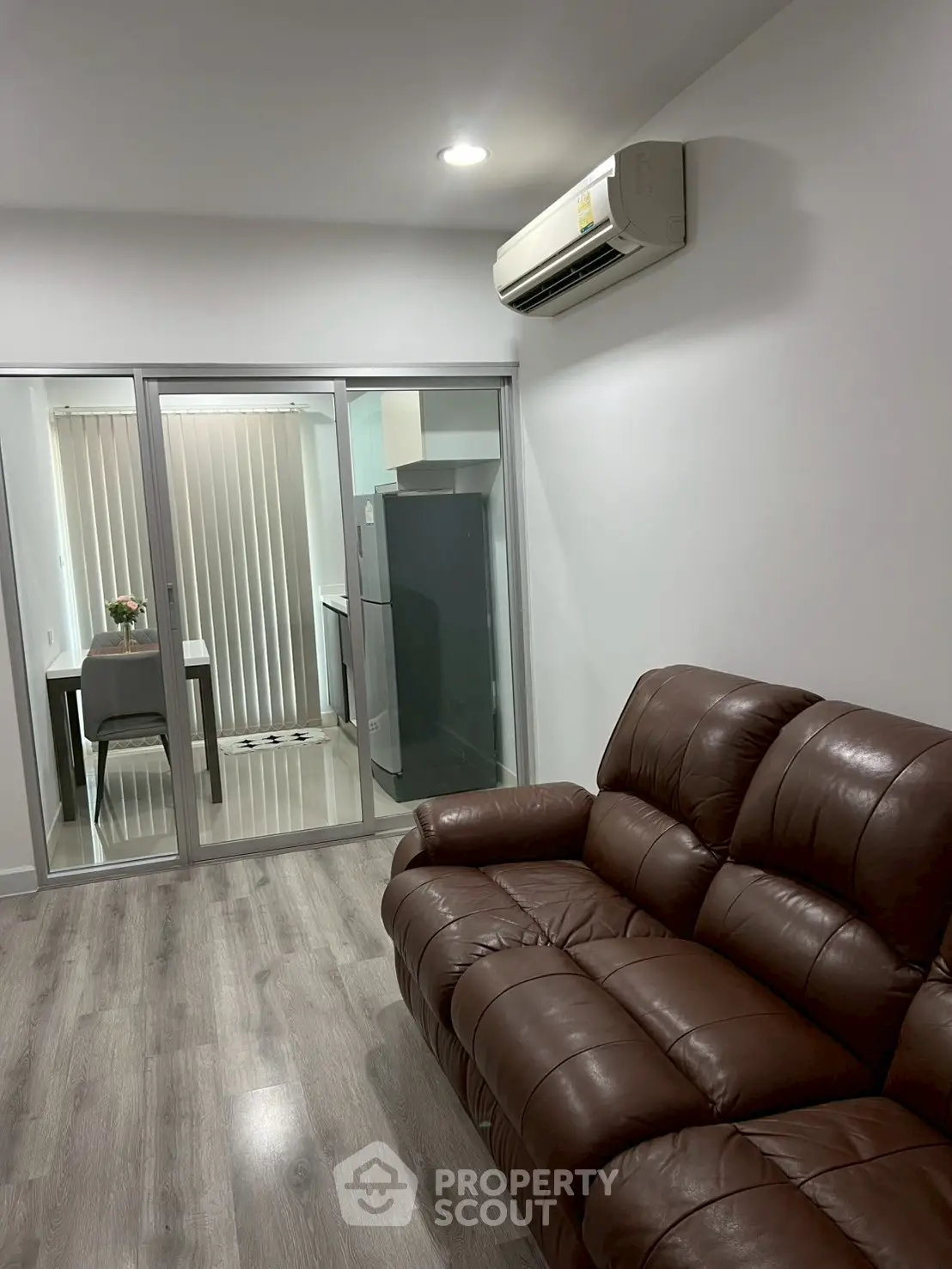 Modern living room with leather sofa and view into a sleek kitchen area.