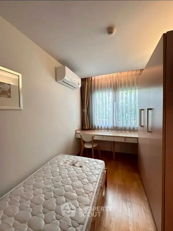 Cozy bedroom with natural light, featuring a single bed, desk, and wardrobe, ideal for a minimalist lifestyle.