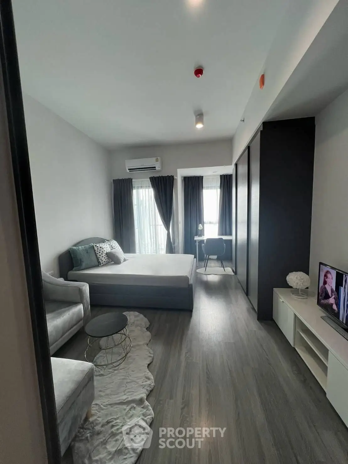 Modern bedroom with sleek design, featuring a cozy bed, stylish furniture, and natural light from large windows.