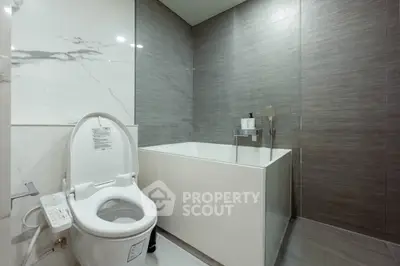 Modern bathroom with sleek design featuring a luxurious bathtub and high-tech toilet.