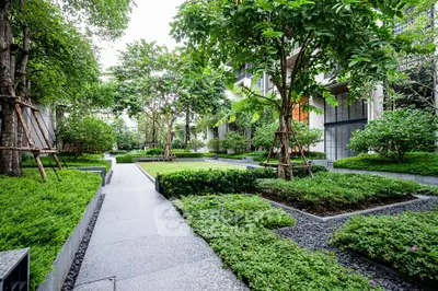 Lush garden pathway in modern residential complex with vibrant greenery and serene ambiance.