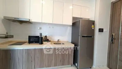 Modern kitchen with sleek cabinetry and stainless steel fridge in a stylish apartment.