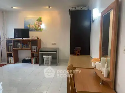 Spacious living area with modern decor and ample natural light, featuring a cozy TV setup and elegant wooden furniture.