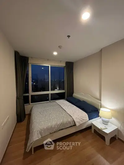 Cozy bedroom with city view, featuring a comfortable bed and ambient lighting.