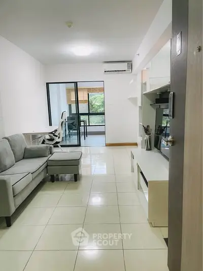 Modern living room with sleek furniture and glass doors leading to a bright balcony.