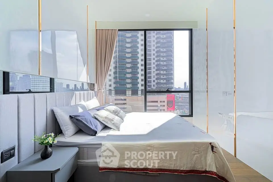 Bright modern bedroom with large window offering stunning city view, featuring elegant decor and cozy bedding.