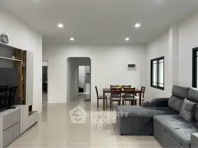 Modern living room with sleek furniture and dining area, perfect for family gatherings.