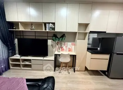 Modern living room with built-in storage, TV, and sleek kitchen area.