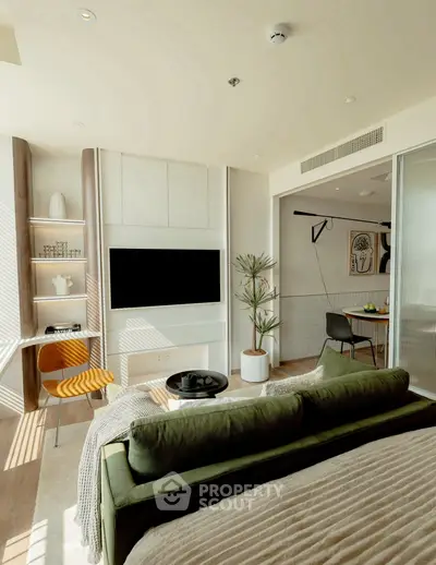 Modern living room with stylish decor and open layout, featuring a cozy green sofa and wall-mounted TV.