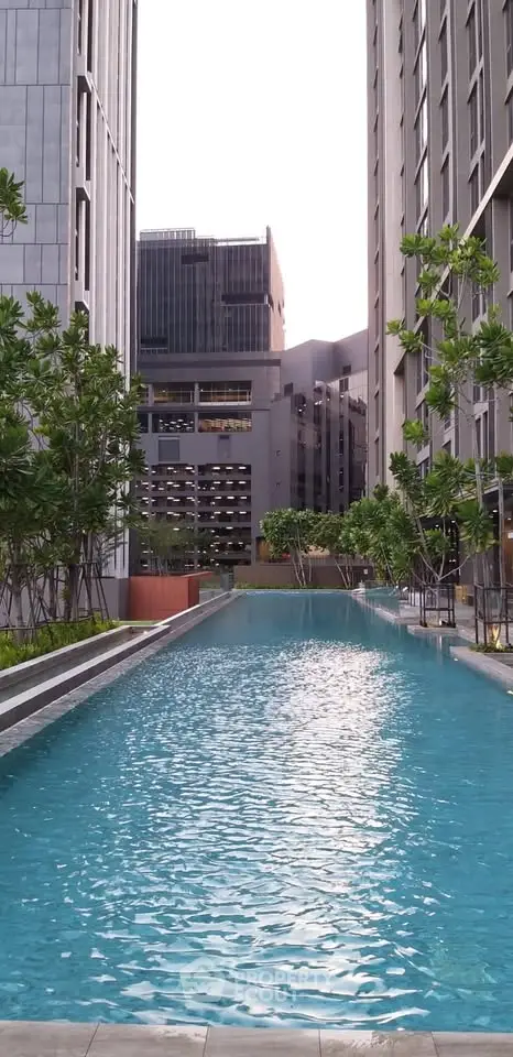 Luxurious urban residential pool surrounded by modern high-rise buildings and lush greenery.