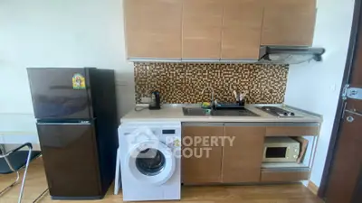 Modern compact kitchen with fridge, washing machine, and stylish backsplash.
