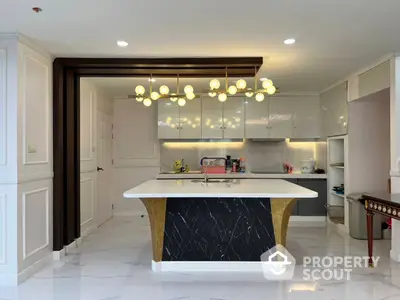 Spacious kitchen with modern design featuring a large central island, elegant marble countertops, and ample lighting for a bright cooking space.