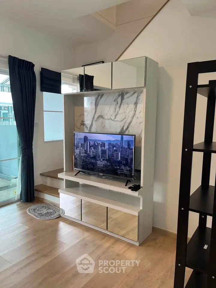 Modern living room with stylish TV unit and large windows for natural light.