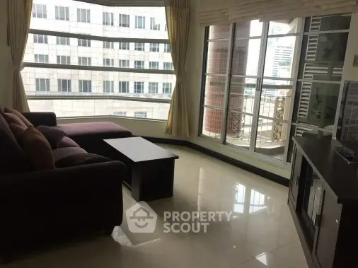 Spacious living room with large windows and modern furniture in a high-rise apartment.