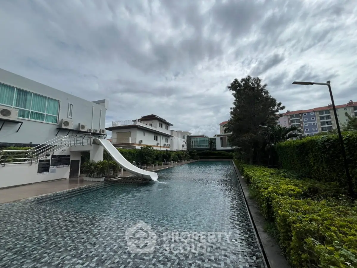 Luxurious residential pool with slide and lush greenery, perfect for relaxation and leisure.