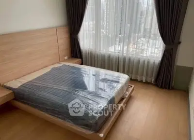 Modern bedroom with city view, featuring a sleek wooden bed and large window with curtains.