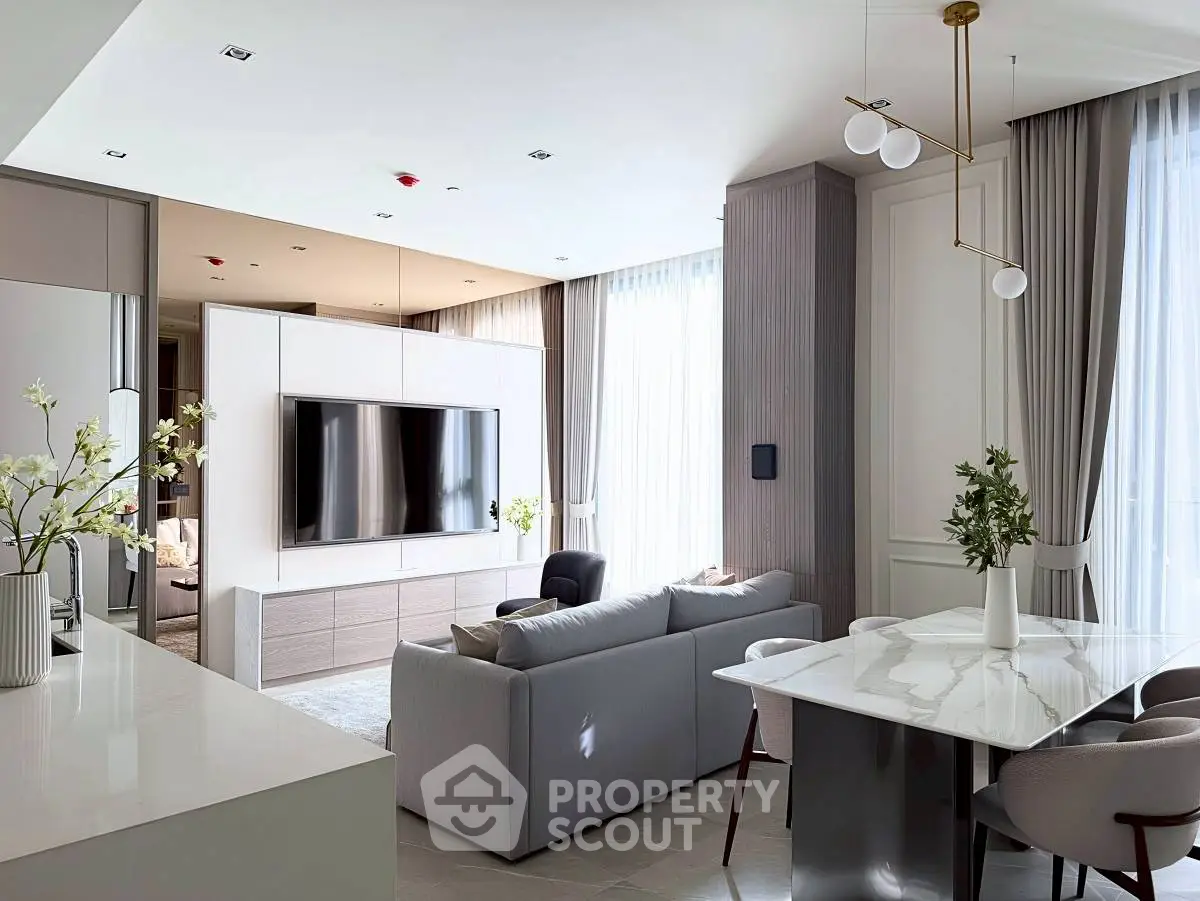 Luxurious modern living room with elegant decor and open layout, featuring a large TV and stylish furniture.