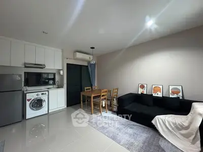 Modern open-plan living room with kitchen, featuring sleek appliances and stylish decor.