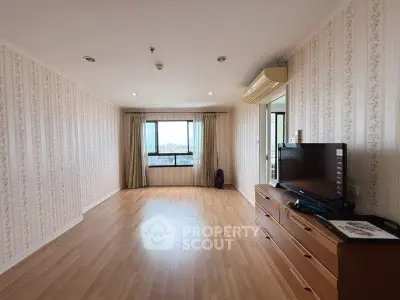 Spacious living room with wooden flooring and large window offering city views.