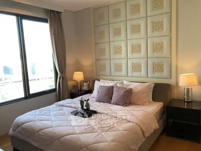 Luxurious bedroom with elegant decor and large window offering city views.