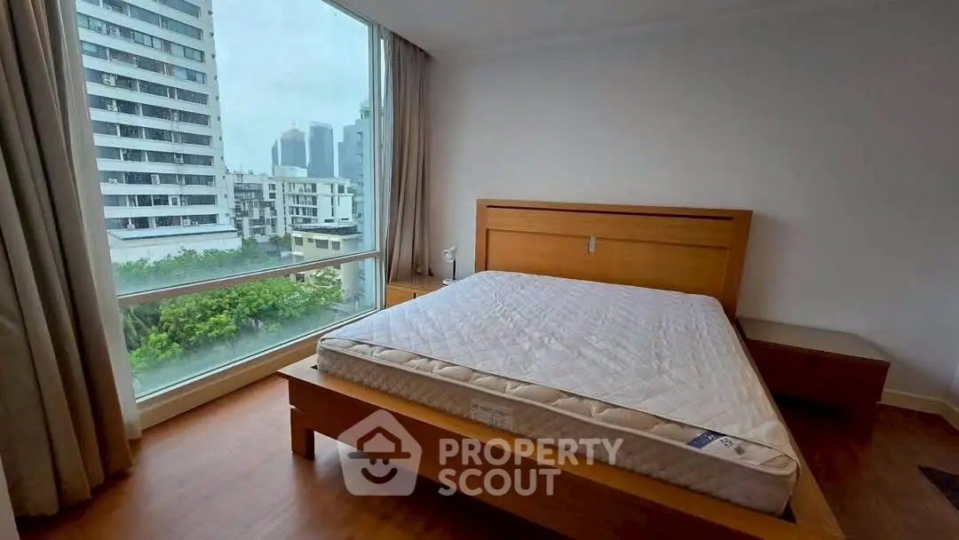 Spacious bedroom with large window offering stunning city views and natural light.
