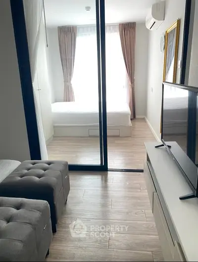 Modern apartment interior with stylish living room and cozy bedroom separated by glass doors.