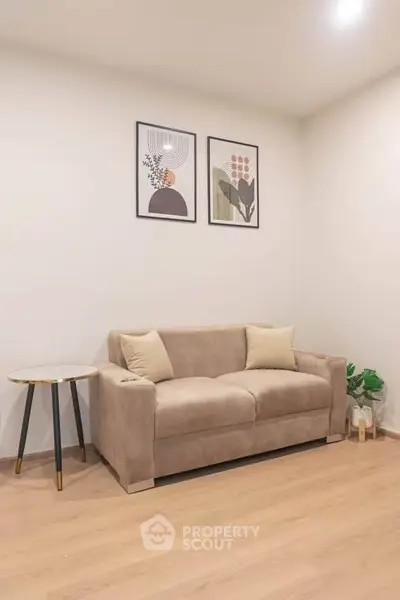 Modern living room with beige sofa, stylish side table, and contemporary wall art.