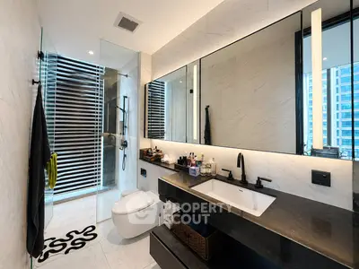 Luxurious modern bathroom with sleek fixtures and large mirror in high-rise apartment.