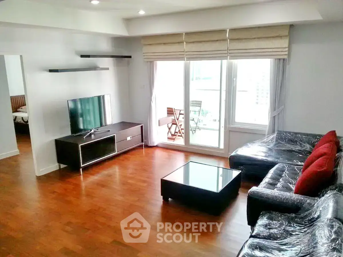 Spacious modern living room with hardwood floors and balcony access in a stylish apartment.