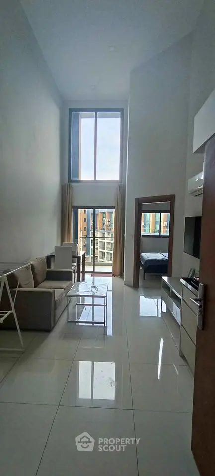 Modern high-ceiling living room with large windows and sleek interior design.