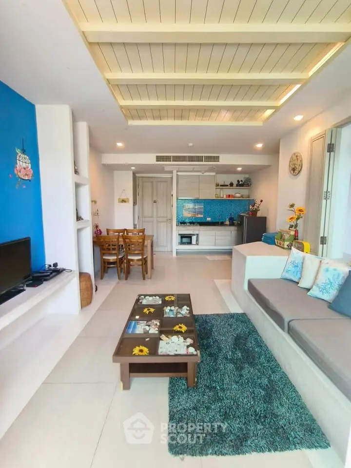 Modern living room with open kitchen, stylish decor, and cozy seating area in a bright apartment.