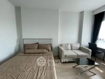 Modern studio apartment with cozy bed and stylish sofa in a bright, minimalist design.