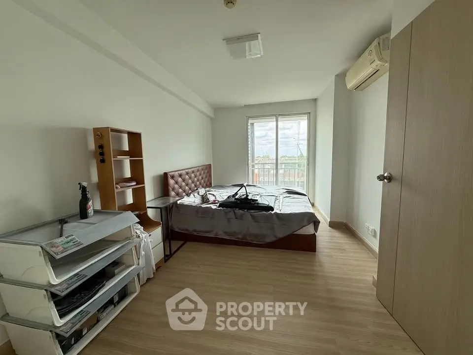 Spacious bedroom with natural light and modern furnishings, featuring a large window with a view.