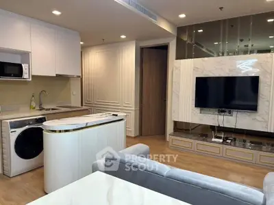 Modern living room with open kitchen, featuring sleek appliances and stylish decor.