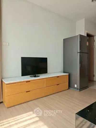 Modern living room with sleek TV stand and stainless steel fridge, perfect for contemporary urban living.