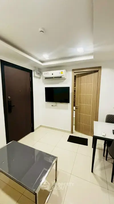 Modern living room with sleek furniture and wall-mounted TV in a cozy apartment.